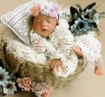 Peaceful newborn baby sleeping in a basket decorated with delicate flowers, creating a serene and heartwarming scene.