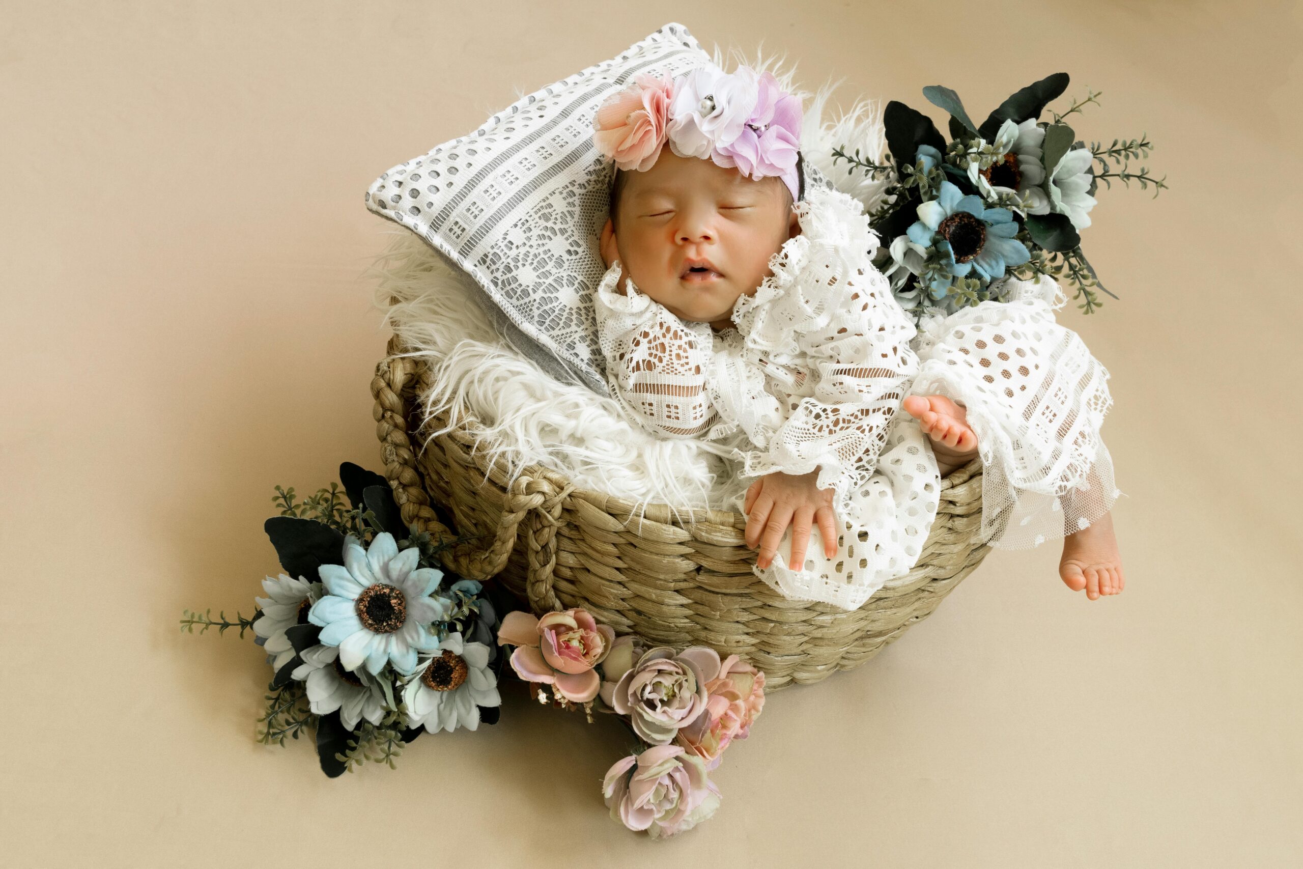 Peaceful newborn baby sleeping in a basket decorated with delicate flowers, creating a serene and heartwarming scene.