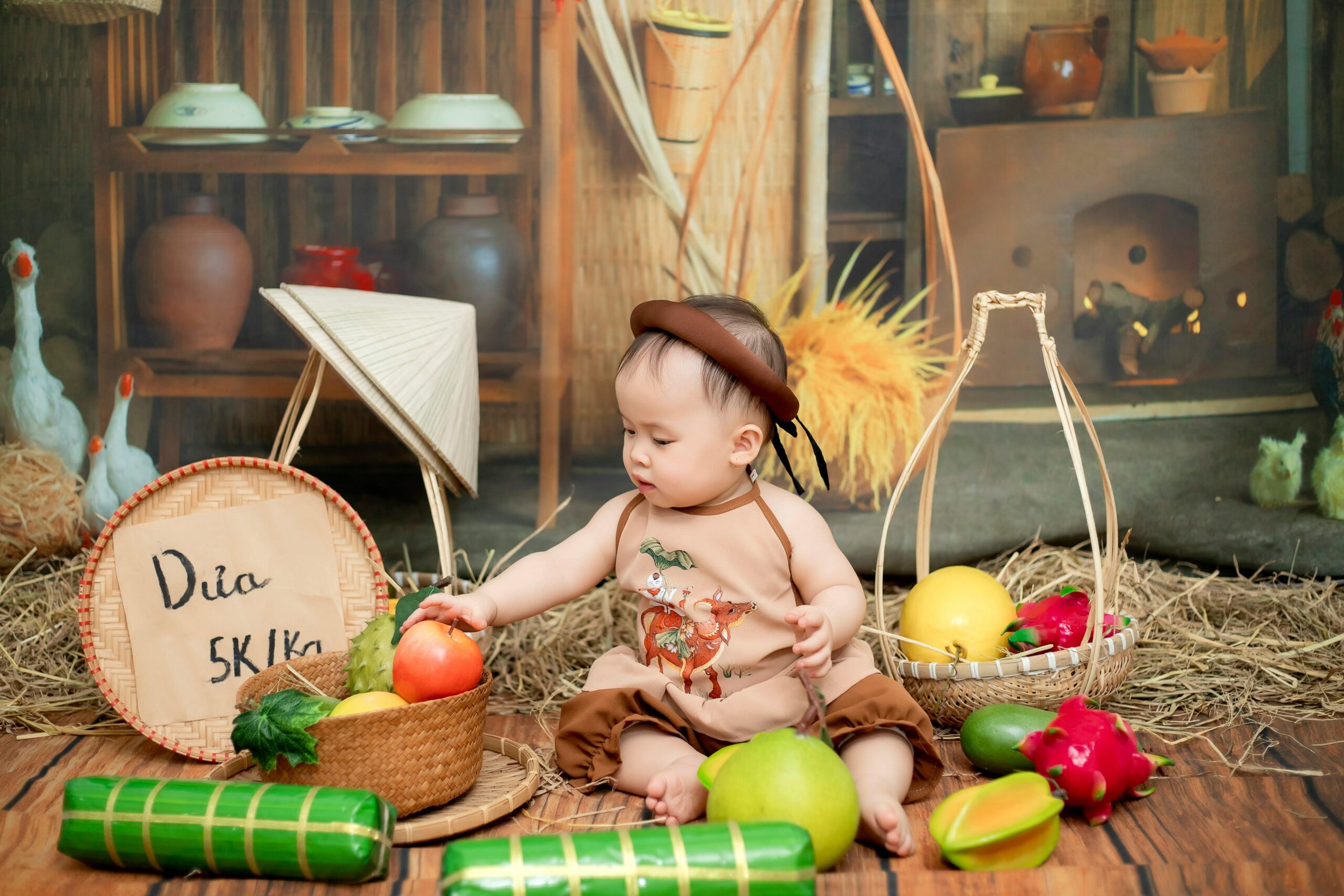 A cute child surrounded by fruits in a rustic, traditional environment.