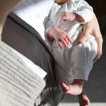 A mother lovingly cradles her newborn in a sunlit room, highlighting tender moments.